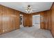 Bedroom with wood paneled walls, ceiling fan and plush carpeting, with doorways to other rooms at 116 Poplar St, Fairburn, GA 30213