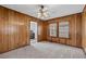 Bedroom with wood paneled walls, two windows for natural light, ceiling fan and plush carpeting at 116 Poplar St, Fairburn, GA 30213