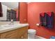 Small bathroom featuring a single sink vanity, toilet, and red paneled walls with matching towels at 210 Meadow View Dr, Grayson, GA 30017