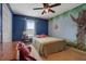 Colorful bedroom featuring tree mural, ceiling fan, and double closet at 210 Meadow View Dr, Grayson, GA 30017