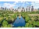 Aerial view of a green space in Atlanta with a body of water surrounded by trees and city buildings in the background at 220 Renaissance Ne Pkwy # 1105, Atlanta, GA 30308