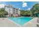Community pool featuring lounge seating, tables with umbrellas, and a grassy area at 220 Renaissance Ne Pkwy # 1105, Atlanta, GA 30308