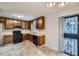 Well-lit kitchen featuring wooden cabinets, black appliances, and a view to the backyard at 11111 Shannon Cir, Hampton, GA 30228