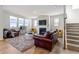 Bright living room featuring a fireplace, plush seating, large windows, and staircase at 4779 Mock Orange Sw St, Atlanta, GA 30331