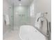 Bright bathroom with a glass enclosed shower, a soaking tub, and a marble surround at 1380 Tennis Court Pl, Roswell, GA 30075