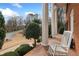 Charming front porch with white columns, brick flooring, and a cozy rocking chair to enjoy the view at 1380 Tennis Court Pl, Roswell, GA 30075