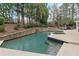 Beautiful pool with a stone retaining wall and lush greenery, creating a serene outdoor retreat at 1380 Tennis Court Pl, Roswell, GA 30075