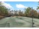 View of the community tennis courts surrounded by trees, with well-maintained green surfaces and lighting at 1380 Tennis Court Pl, Roswell, GA 30075