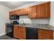Cozy kitchen featuring granite counters, wood cabinets, and black appliances at 3552 Meadowview Dr, Lithia Springs, GA 30122