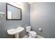 Neutral-toned half bathroom with pedestal sink, toilet, and framed mirror; perfect for guests at 215 Odyssey Turn, Conyers, GA 30012