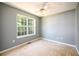 This carpeted bedroom is brightly lit with a window and a ceiling fan at 215 Odyssey Turn, Conyers, GA 30012