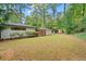 View of a spacious backyard with a lush lawn, mature trees, and a white brick house with a deck at 3363 Briarcliff Ne Rd, Atlanta, GA 30345