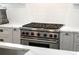 Close up of kitchen featuring stainless steel range with red knobs, white subway tile, and marble countertops at 210 Calypso Cir, Atlanta, GA 30305