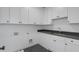 A well-equipped laundry room features white cabinetry, dark countertops, and herringbone flooring at 262 Green Hill Ne Rd, Sandy Springs, GA 30342