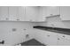 Well-lit laundry room with white cabinets, dark countertops, and modern black herringbone tile flooring at 262 Green Hill Ne Rd, Sandy Springs, GA 30342