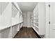 Bright walk-in closet featuring wood floors, white shelving, and metal hanging rods, perfect for organizing your wardrobe at 262 Green Hill Ne Rd, Sandy Springs, GA 30342