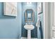 Stylish half bath with a pedestal sink, decorative mirror, and serene blue walls at 1262 Park Pass Row, Suwanee, GA 30024