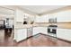 Well-lit kitchen with stainless steel appliances, white cabinetry, granite countertops and hardwood floors at 1262 Park Pass Row, Suwanee, GA 30024