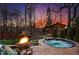 Scenic backyard featuring a hot tub, fire pit, water feature, and lush landscaping under a colorful sunset at 1352 Middlesex Ne Ave, Atlanta, GA 30306