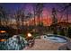 Backyard with hot tub, fire pit, mature trees and professional landscaping, illuminated by an evening sky at 1352 Middlesex Ne Ave, Atlanta, GA 30306