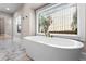 Bright bathroom featuring free-standing tub, marble floors and large windows overlooking outdoor scenery at 1352 Middlesex Ne Ave, Atlanta, GA 30306