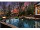 Luxurious pool and spa area with fire bowls and cabana amidst mature trees and landscape lighting at 1352 Middlesex Ne Ave, Atlanta, GA 30306