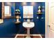 Stylish bathroom with a pedestal sink, decorative shelves, and a unique blue wall color at 2250 Snug Ne Hbr, Marietta, GA 30066