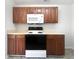 A clean kitchen showcasing a range, microwave, and wooden cabinetry against a white wall at 11403 S Grove Dr, Hampton, GA 30228