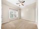 A large bedroom with neutral carpet, ceiling fan, and natural light from the window at 1416 Elgin Way, Cumming, GA 30041