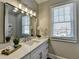 Elegant bathroom with a large mirror, white vanity, marble countertop, and a window providing natural light at 4634 Meadow Bluff Ln, Suwanee, GA 30024