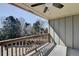 Covered outdoor patio featuring a ceiling fan and wood railings overlooking beautiful trees and blue skies at 4634 Meadow Bluff Ln, Suwanee, GA 30024