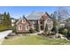 Stately brick home with manicured lawn, mature trees, and classic design elements under a bright blue sky at 4235 Iron Duke Ct, Peachtree Corners, GA 30097