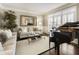 Elegant living room showcasing a grand piano, a comfortable sofa, and bright natural light from shuttered windows at 4235 Iron Duke Ct, Peachtree Corners, GA 30097