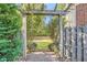 View of a backyard with a pergola over a brick walkway, leading to a grassy lawn and a wood fence at 4742 Balmoral Ne Way, Marietta, GA 30068