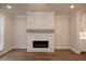 Close-up of the stone fireplace with a wood mantel, complemented by hardwood floors at 133 Ward'S Crossing Way # 18, Johns Creek, GA 30022