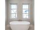 Elegant bathroom with a soaking tub positioned beneath two windows that provide natural light at 145 Cedarwood Ln, Roswell, GA 30075