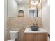 Stylish powder room showcasing a unique stone accent wall, vessel sink, modern faucet, and elegant lighting fixtures at 145 Cedarwood Ln, Roswell, GA 30075