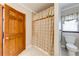 Bathroom featuring a shower stall with a beige curtain, white toilet and wood door at 1980 Two Springs Way, Lawrenceville, GA 30043