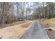 View of home showing driveway and natural landscaping with mature trees and seasonal flowers at 1980 Two Springs Way, Lawrenceville, GA 30043