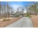View of the home featuring attached garage, long driveway and natural surroundings at 1980 Two Springs Way, Lawrenceville, GA 30043