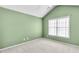 Minimalist bedroom with soft green walls, neutral carpet, a window bringing in natural light, and electrical outlets at 2964 Perimeter Cir, Buford, GA 30519
