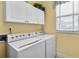Bright laundry room featuring a white washer and dryer with overhead cabinets at 2964 Perimeter Cir, Buford, GA 30519