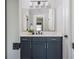Stylish bathroom with navy blue cabinets, marble countertops, and a decorative mirror at 906 Bingham St, Woodstock, GA 30188