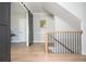 Hallway with sliding barn door and light wood floors leading to the staircase at 906 Bingham St, Woodstock, GA 30188