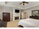 Bright main bedroom featuring a fireplace, TV, ceiling fan, carpet flooring, and white bedding at 2871 Parkridge Ne Dr, Brookhaven, GA 30319