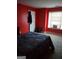 Cozy bedroom features a comfortable bed, bright window, and vibrant red walls at 3551 Northgate Cv, Ellenwood, GA 30294