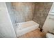 Neutral-toned bathroom featuring a white bathtub with tiled walls and flooring at 1690 Carter Rd, Decatur, GA 30032