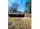 Backyard view of home with brick detail and a patio surrounded by lush greenery at 2182 Rosewood Rd, Decatur, GA 30032