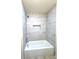 A well-lit bathtub featuring marble-style tiling, modern fixtures, and a recessed shelf at 2182 Rosewood Rd, Decatur, GA 30032