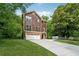 Attractive two-story house featuring shingle siding, brick accents, and a spacious driveway, surrounded by lush greenery at 1303 N Druid Hills Ne Rd, Brookhaven, GA 30319